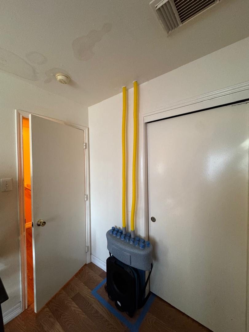 Air movers and dehumidifiers drying a hallway with ceiling water damage