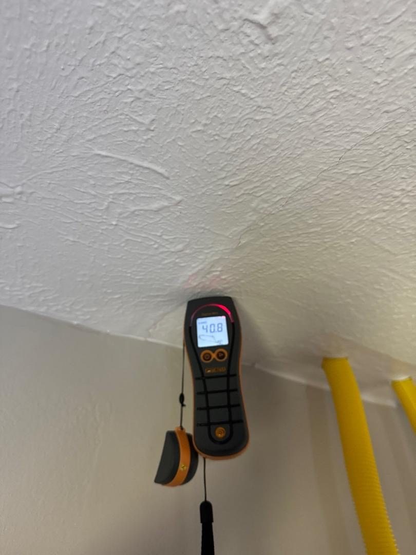 Moisture meter reading on a water-stained ceiling